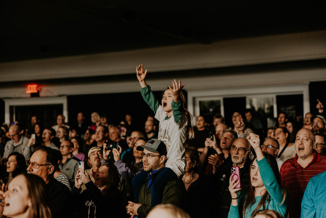 Child in crowd with hands up